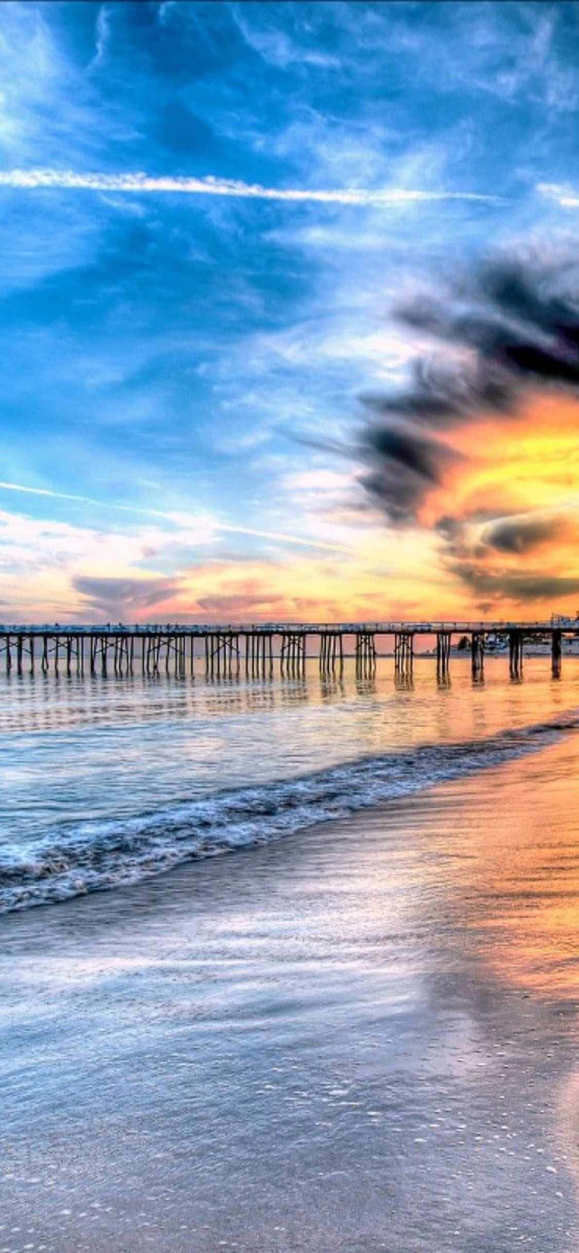 a pier with a sunset over the ocean Bakgrunner