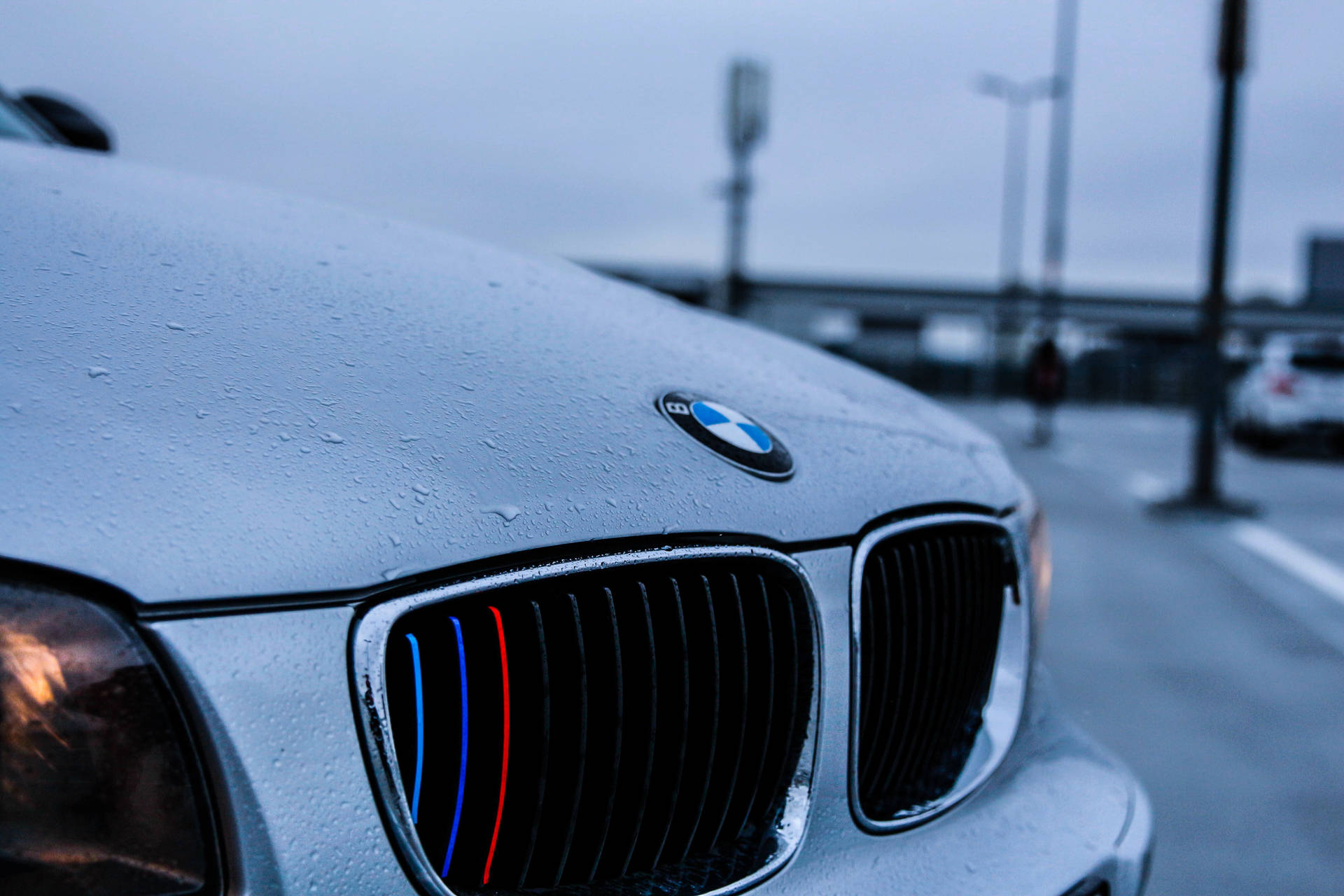 Nærbilde bakgrunnsbilde av hvit BMW-bilpanser med regndråper