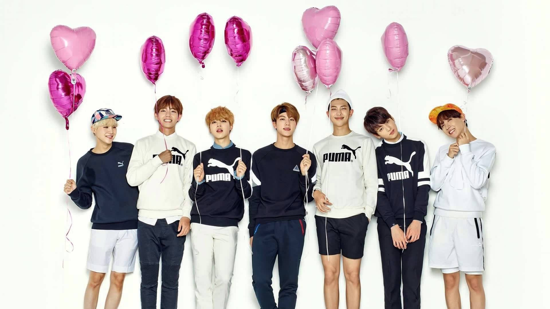 BTS smiler og holder et hjerteballong-bakgrunnsbilde.
