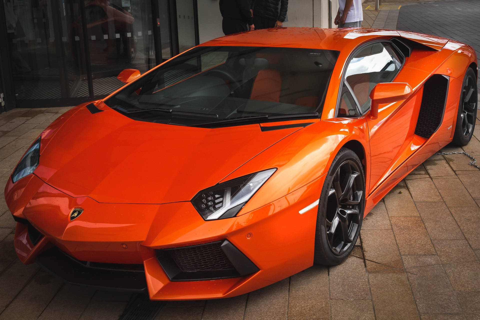 Oransje Lamborghini Aventador forfra og fra siden bakgrunn.