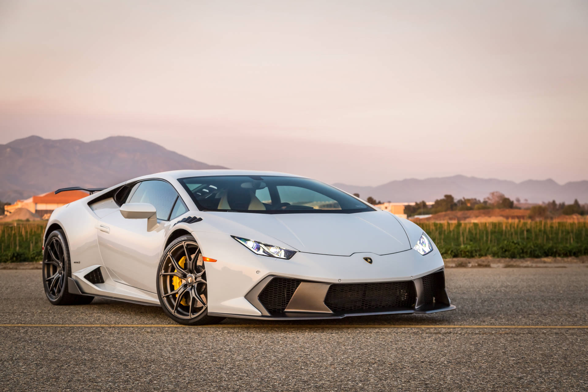 Hvit Lamborghini Huracan ved solnedgang bakgrunnsbilde.