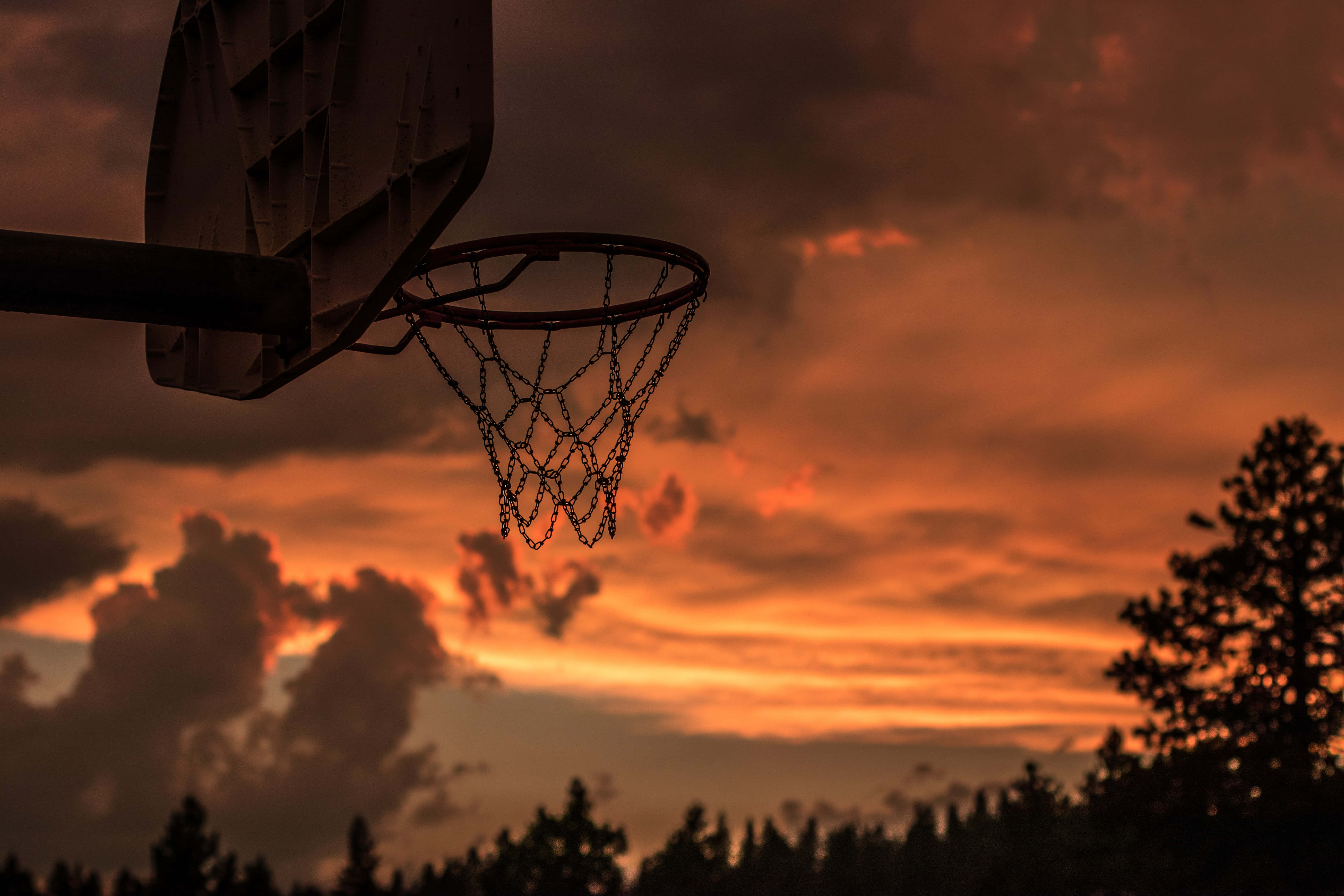 En basketballkurv med solnedgangshimmel bak Bakgrunner