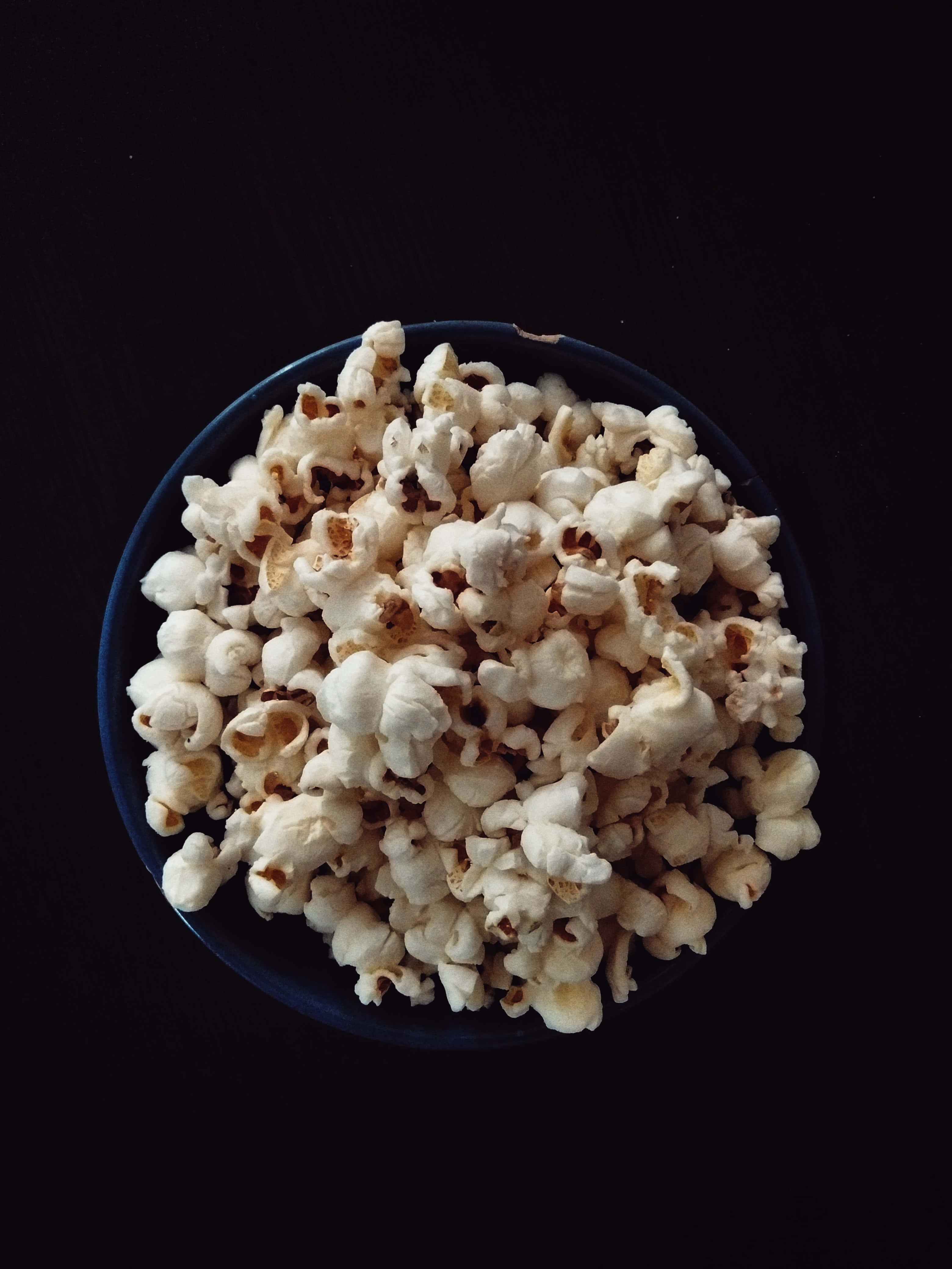 en bolle med popcorn på et svart bord Bakgrunner
