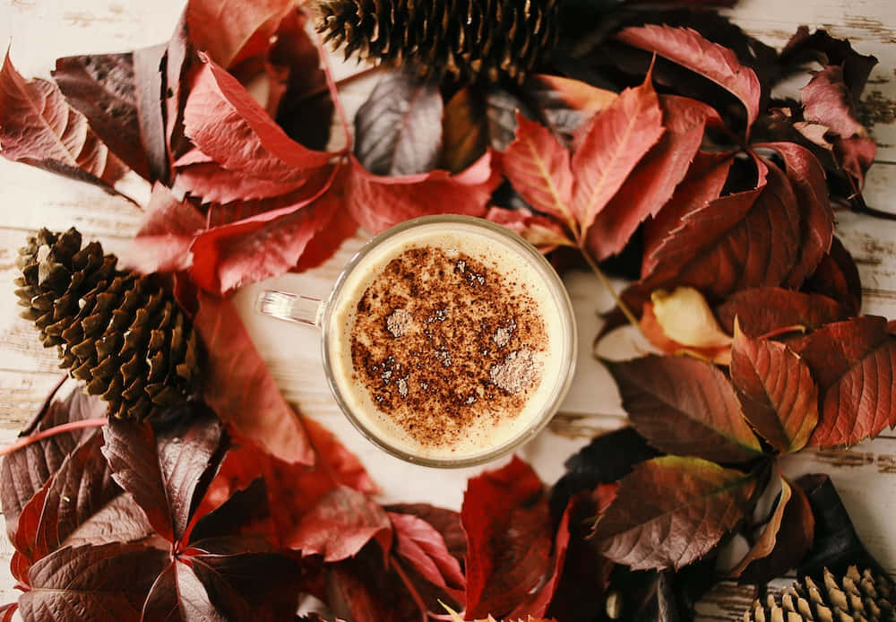 en kopp kaffe omgitt av blader og kongler Bakgrunner