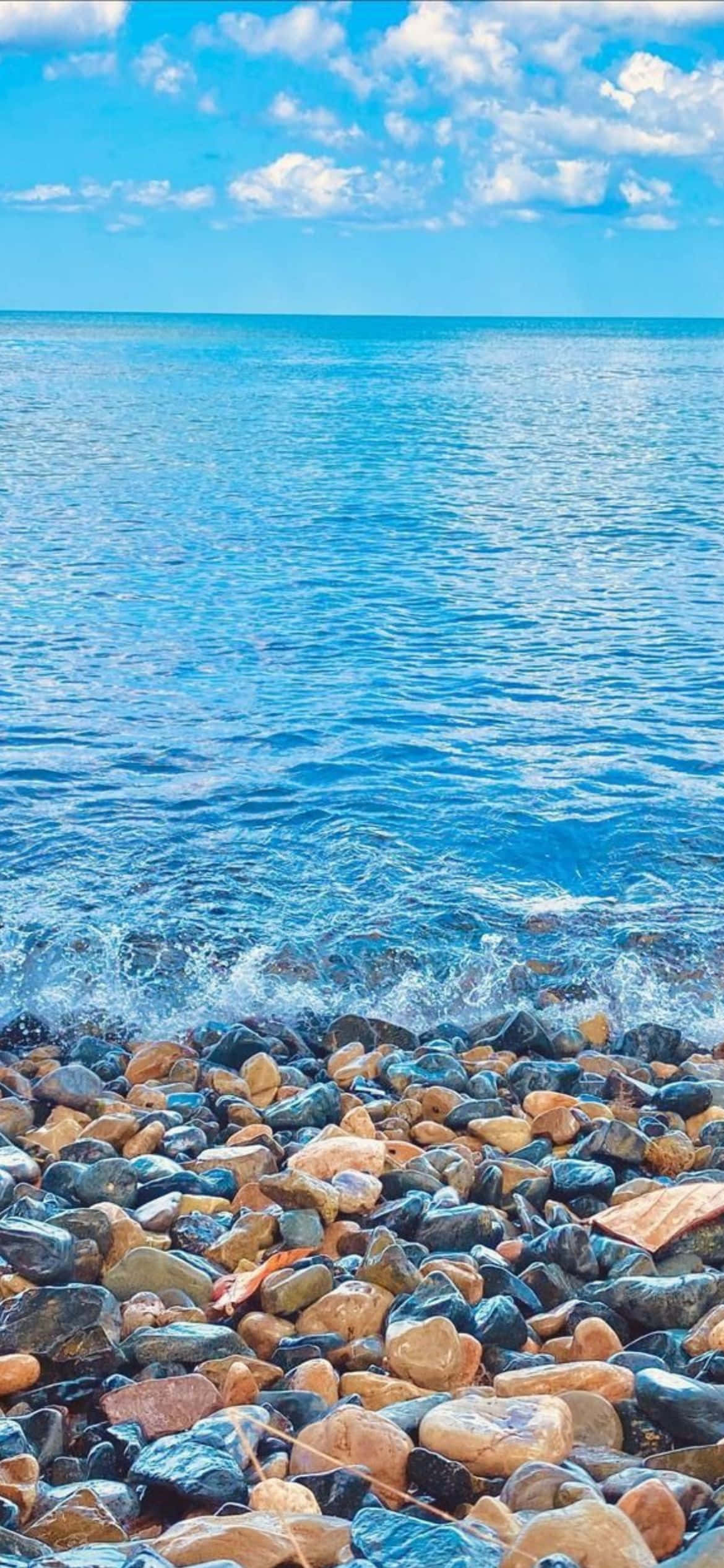 en strand med steiner og vann Bakgrunner