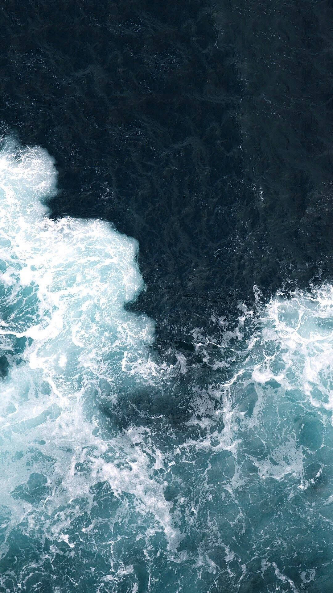 Et fugleperspektiv av havets kraft når bølgene bryter mot stranden. Bakgrunner