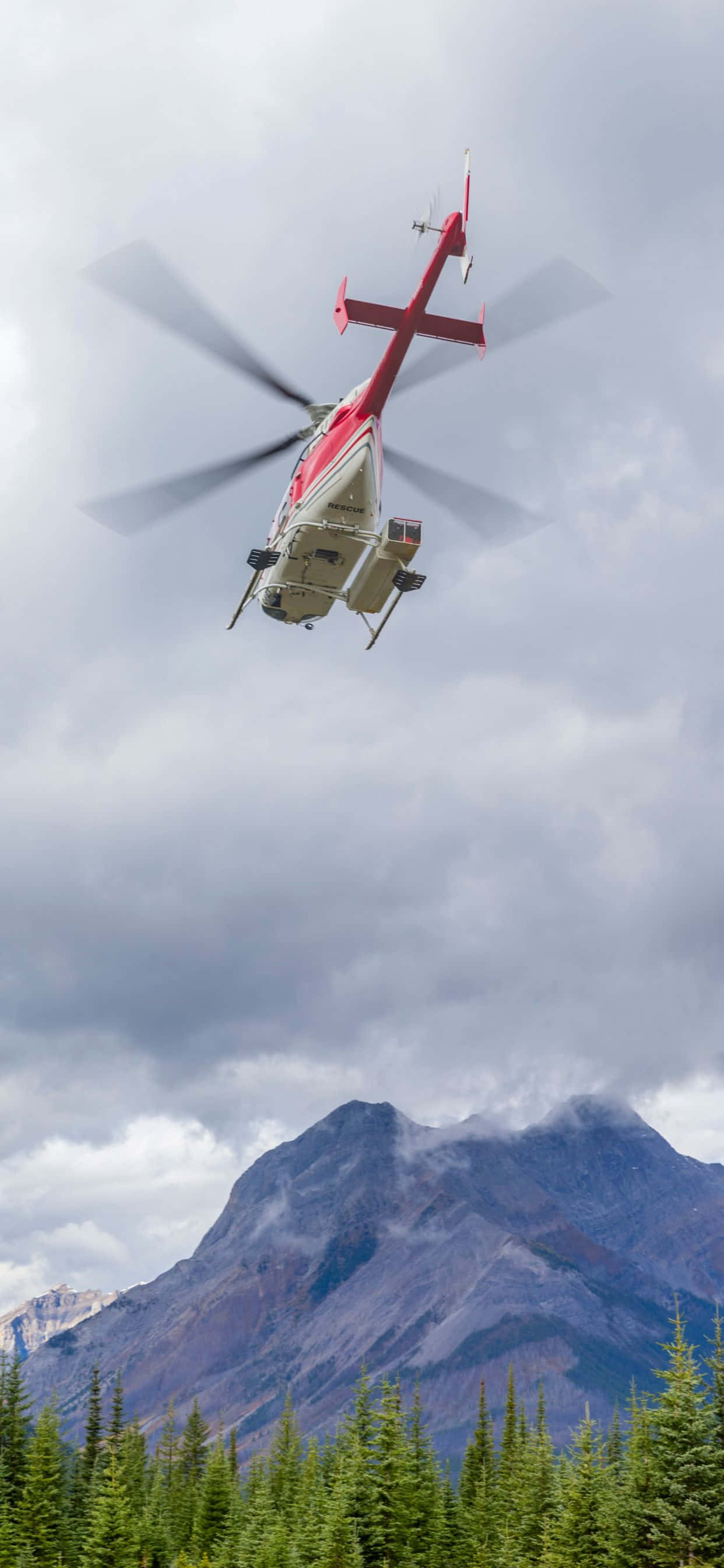 et helikopter som flyr over en skog med fjell i bakgrunnen Bakgrunner