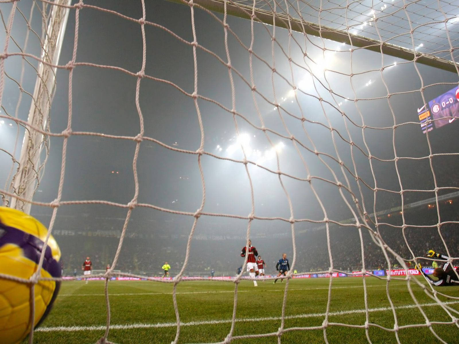 Fotballnett mål med spillere på banen bakgrunn.