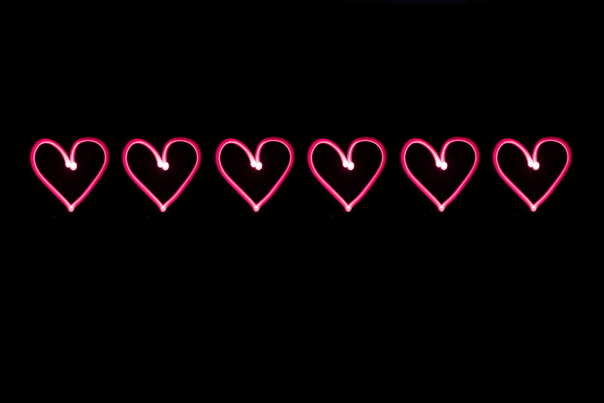 Rosa neonhjerter tegnet på en svart bakgrunn for Valentinsdagen. Digital kunst for din kjærlighet.