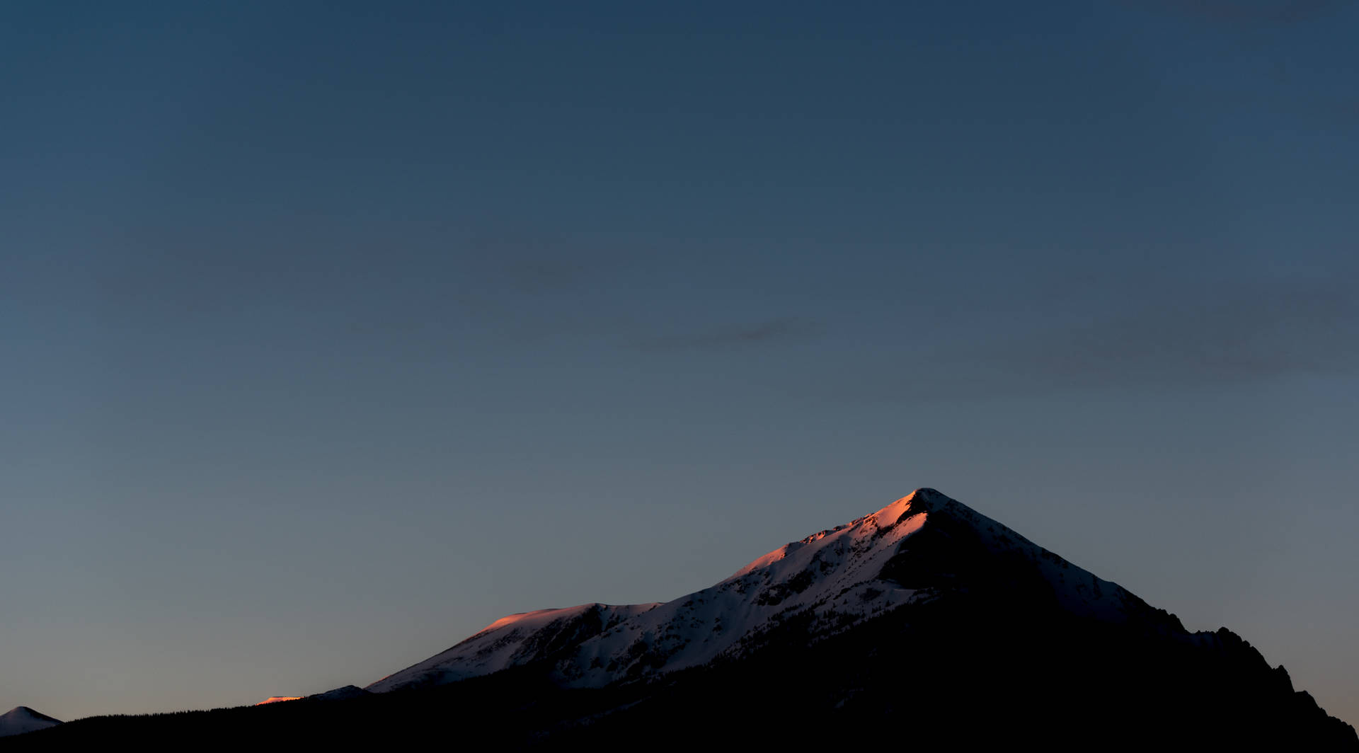 Fjelltopp med skygge og klar himmel før natten.