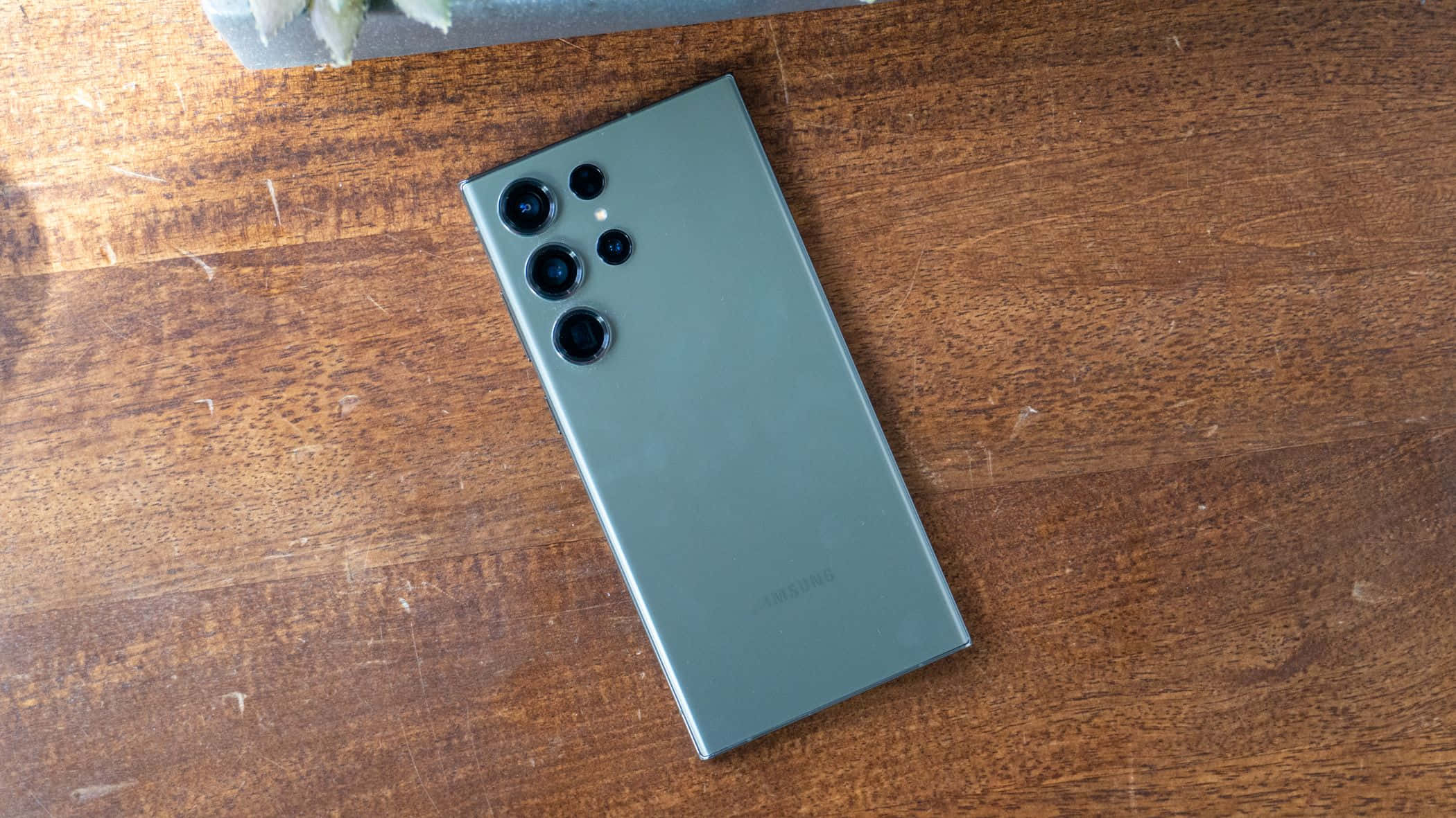 Samsung S23 Ultra grønn bakside med kameraoppsett på treoverflate Bakgrunner