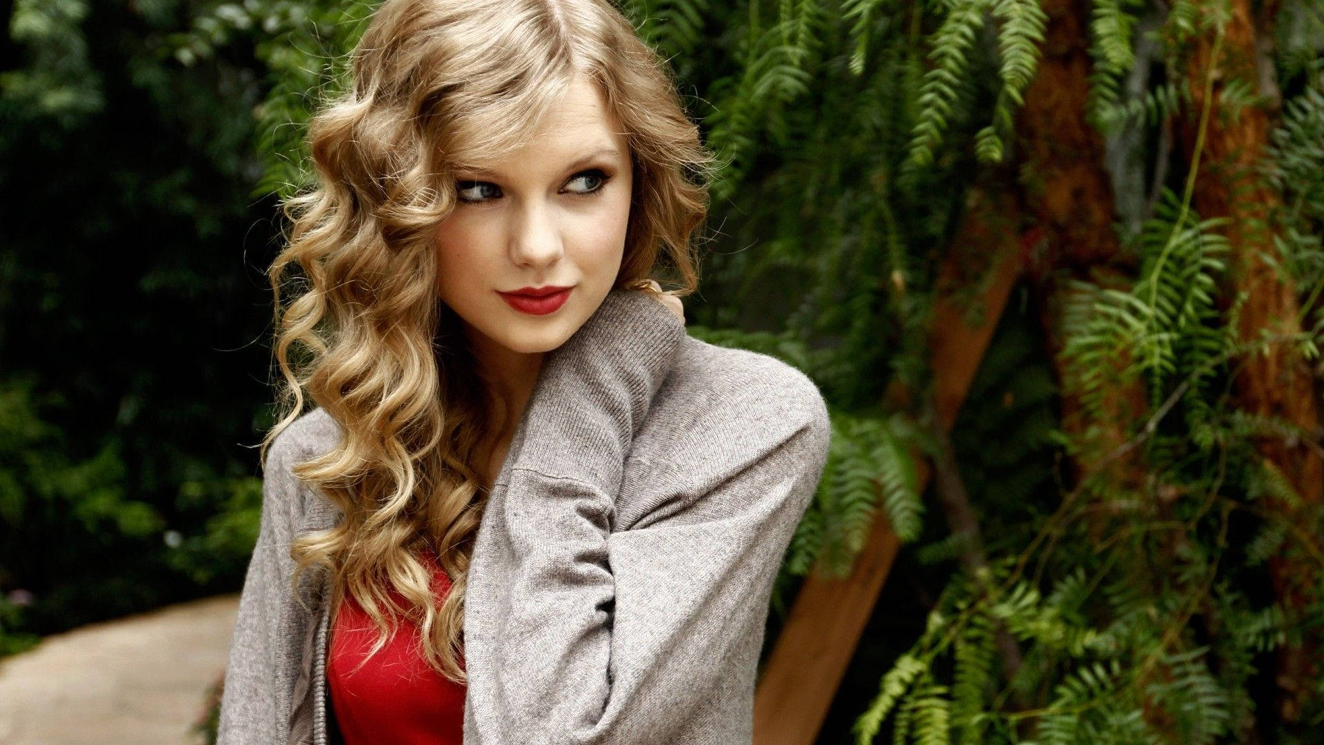Pen søt krøllete Taylor Swift sideblikk-positur bakgrunnsbilde.