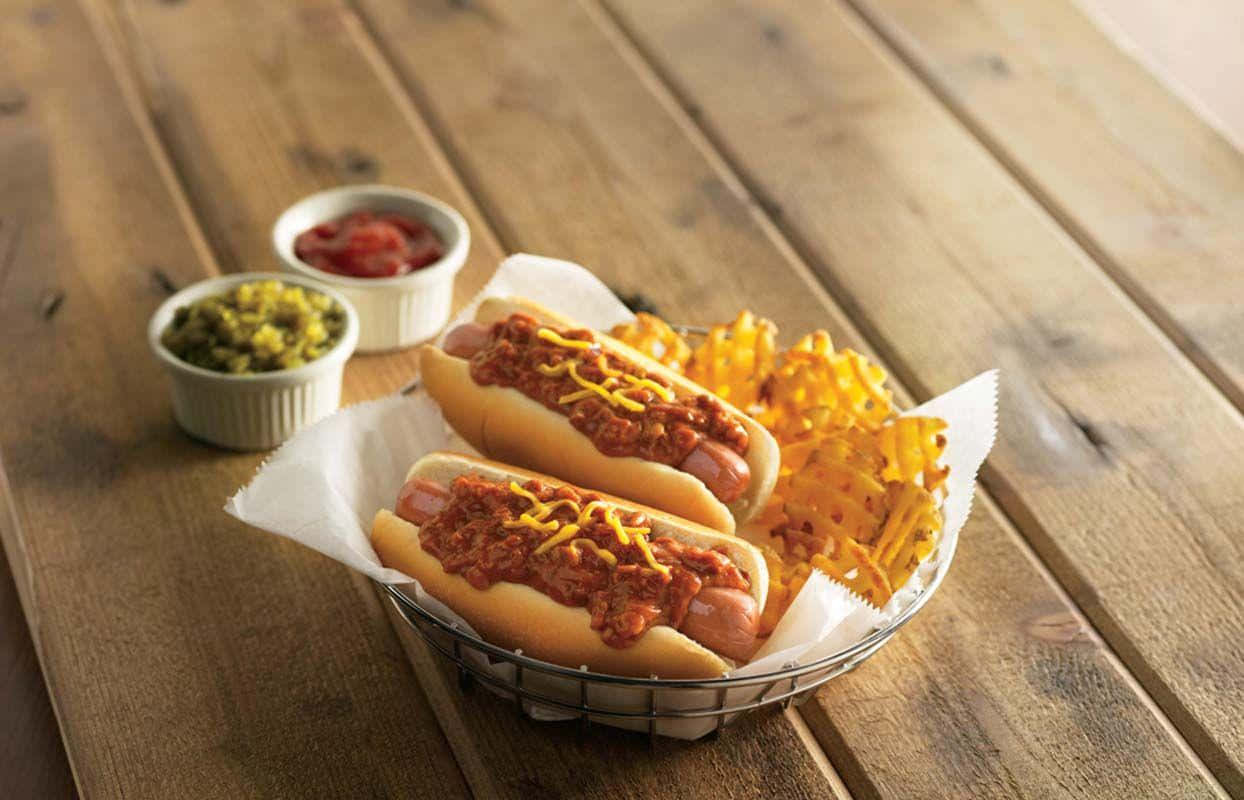 to pølser i en kurv med pommes frites og chili Bakgrunner