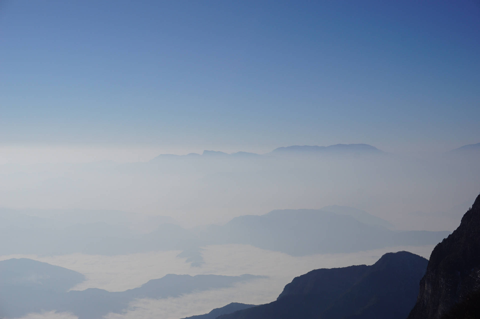 Fjellhimmel med tåke og dis som skjuler landene nedenfor.