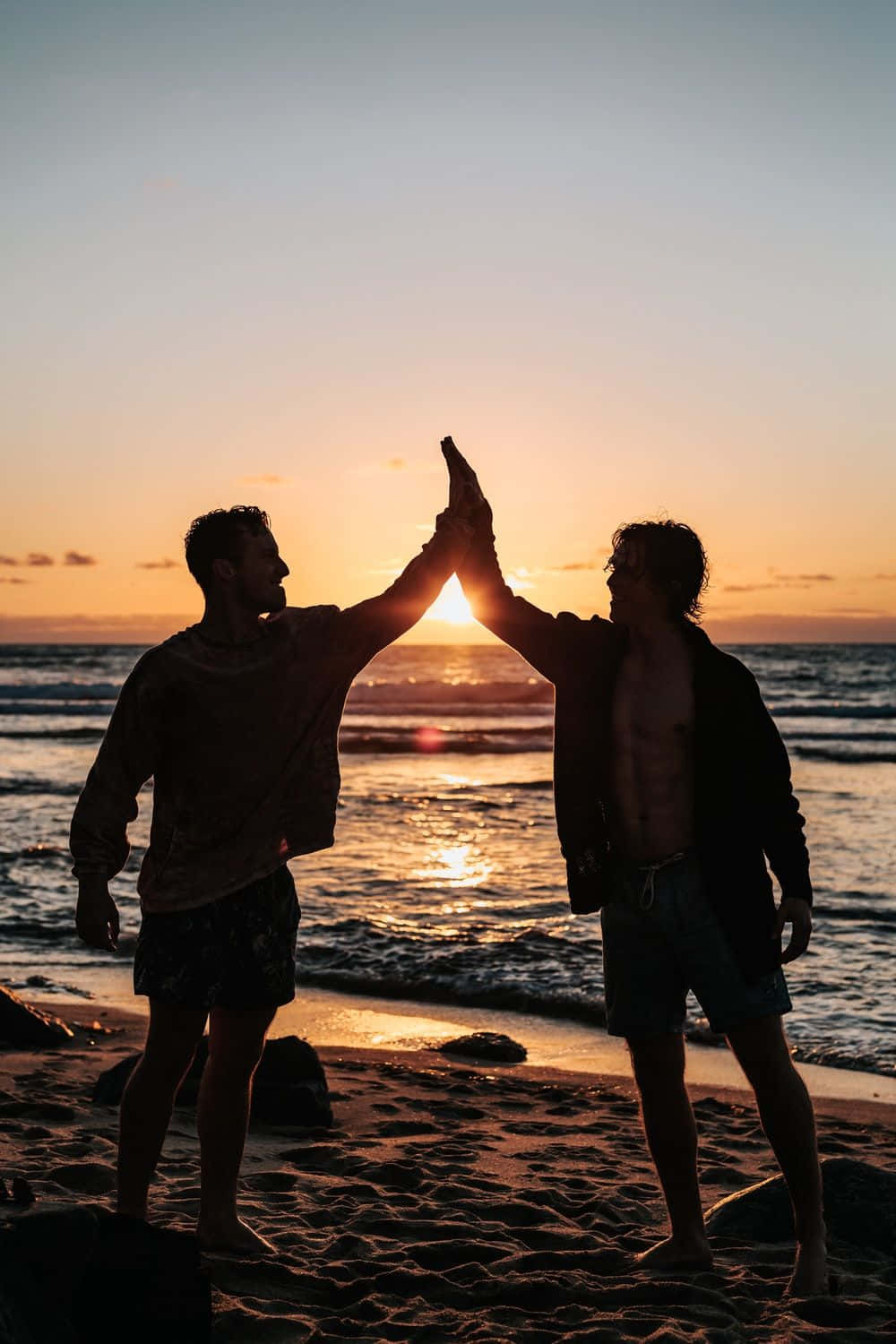 Vennskap high five på stranden ved solnedgang Bakgrunner