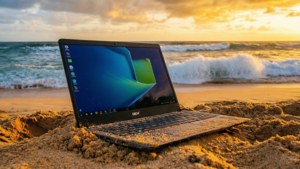 En Chromebook som hviler på en sandstrand under en fantastisk solnedgang.
