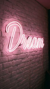 Et lyserødt neonskilt med teksten 'Dream' som lyser opp en hvit murvegg, inspirerende og estetisk. — Lyserosa estetikk Bakgrunner