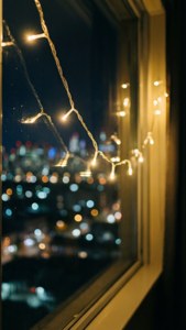 Eventyrlys ved et vindu med bybokeh om natten. — Estetisk jul Bakgrunner