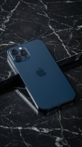 iPhone 17 i midnattblått på marmor, minimalistisk studiobilde.