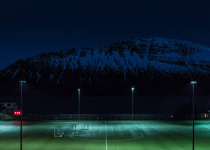 Nattfotballbane opplyst av lysstolper bakgrunn
