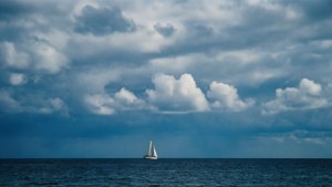 Tungt skydekke over havet med en seilbåt, fredelig maritim bakgrunn. — Himmelutsikt Bakgrunner