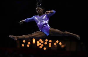 Simone Biles i splitt i luften-bakgrunn — Batterisparing Bakgrunner