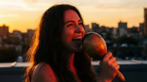 Vivo fremfører en inderlig sang på et tak mens solen går ned, maracas i hånden.