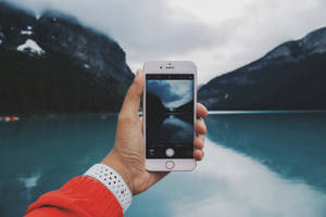 person som tar bilde av en innsjø — iPhone 8 Bakgrunner
