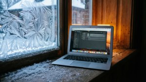 En MacBook Air på en snødekt vinduskarm med koselig innendørsbelysning. — MacBook Bakgrunner